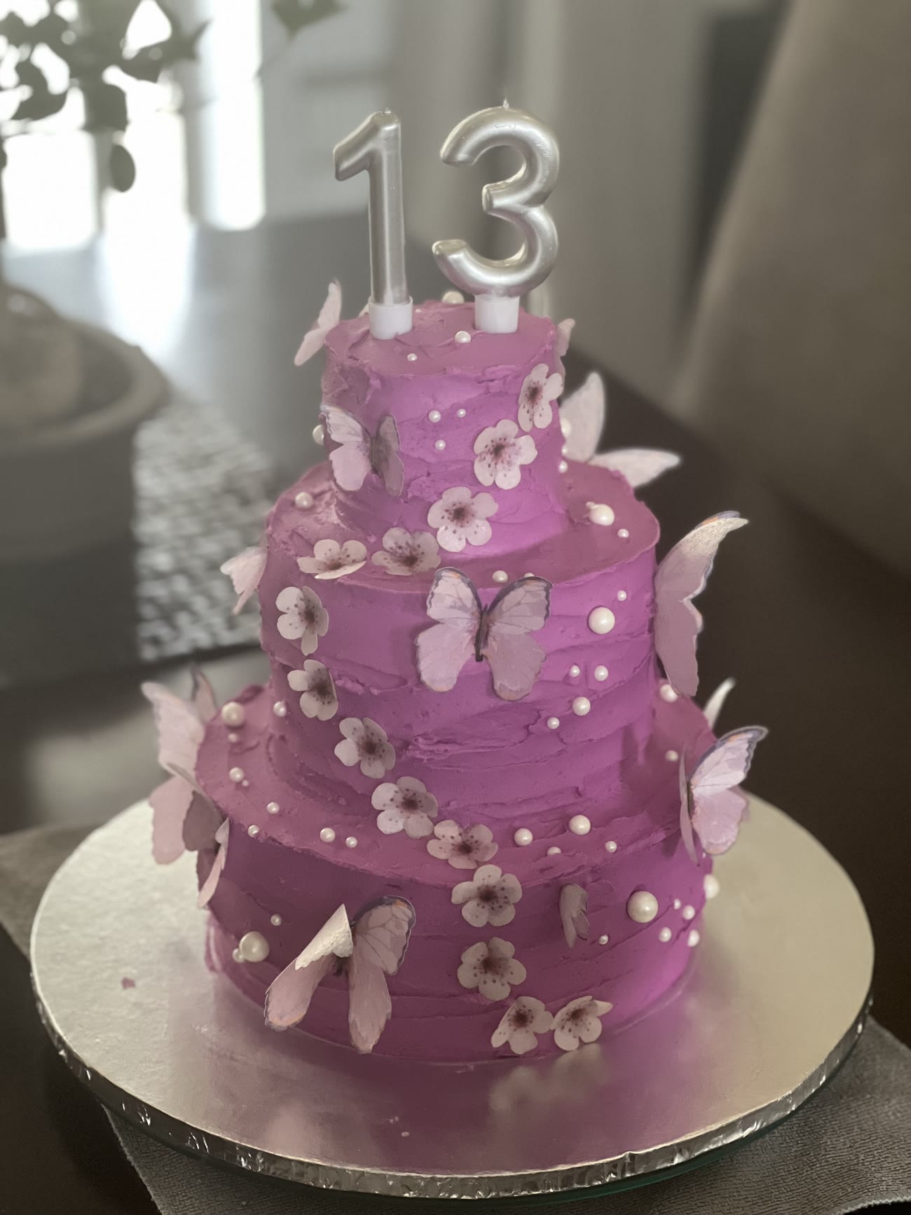 A three tier pink buttercream cake with wafer butterflies and blossom.