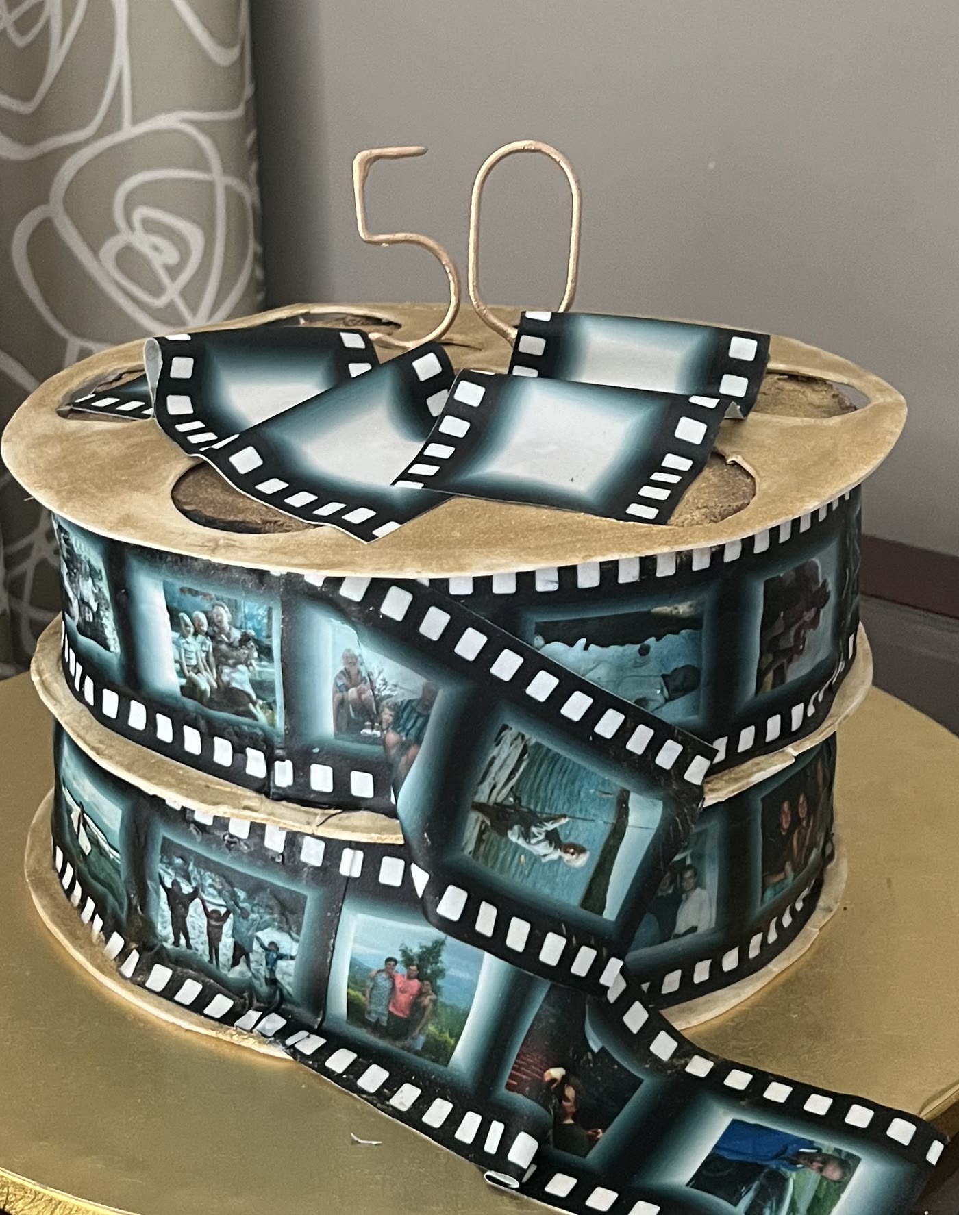 A round cake wrapped in a film strip, with a fiftieth birthday topper.