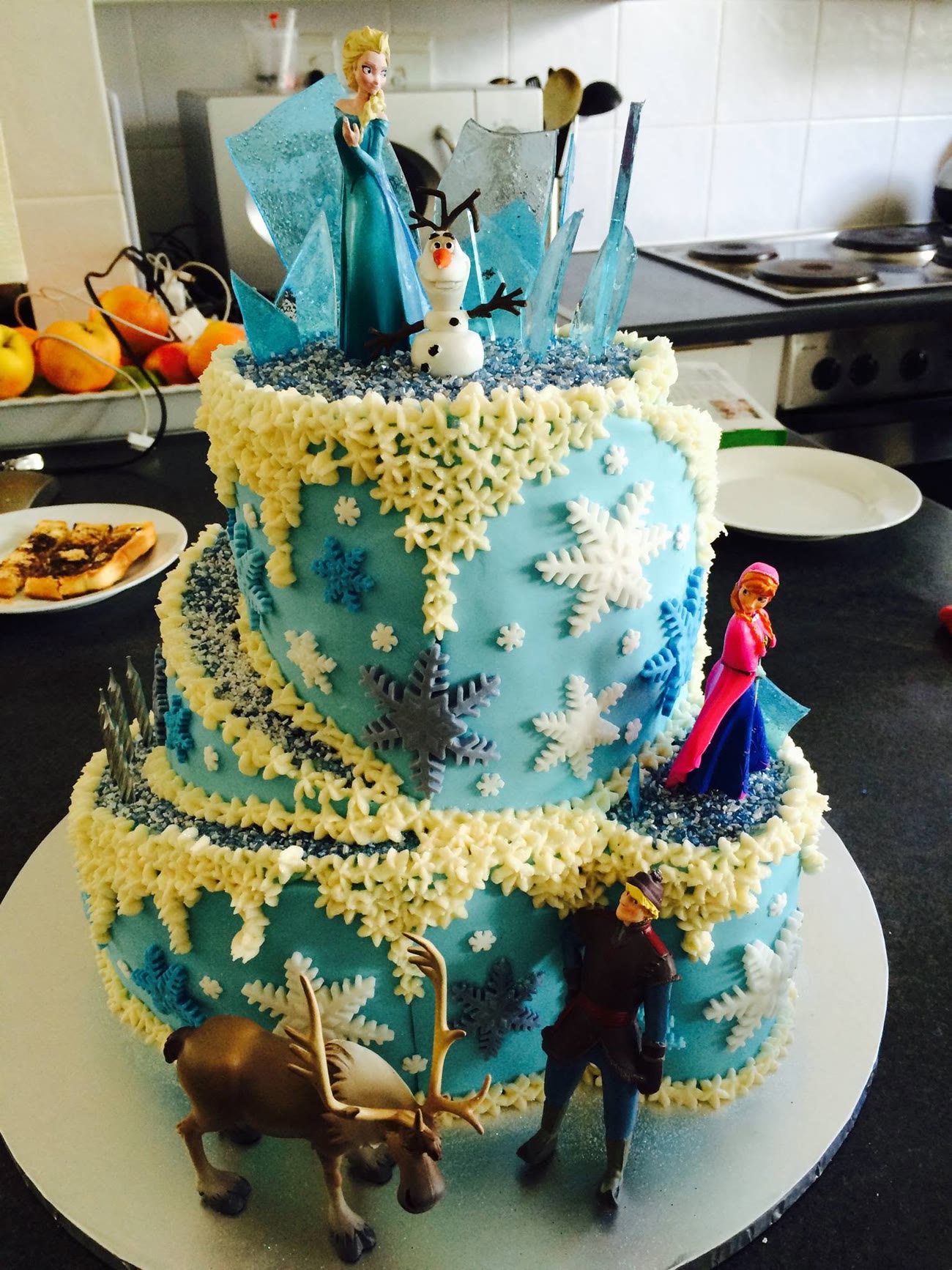 A three tier pale blue cake with piped lace and cut snowflakes.