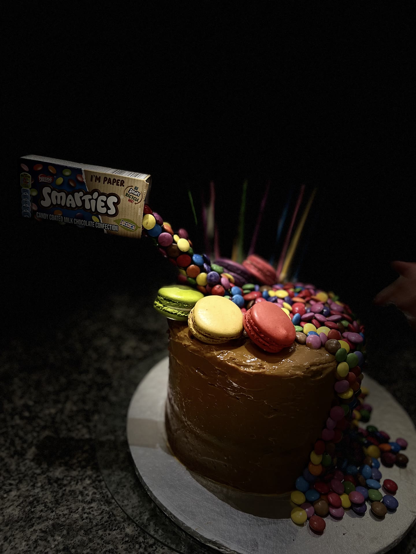 A chocolate cake with sweets appearing to pour from a suspended box.