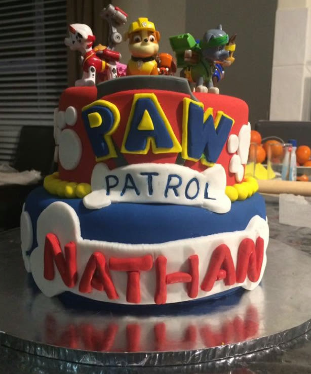 A two tier cake with a shield badge and cut lettering.