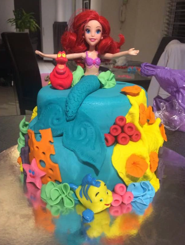 A bright reef cake with cut coral, fish and a doll.