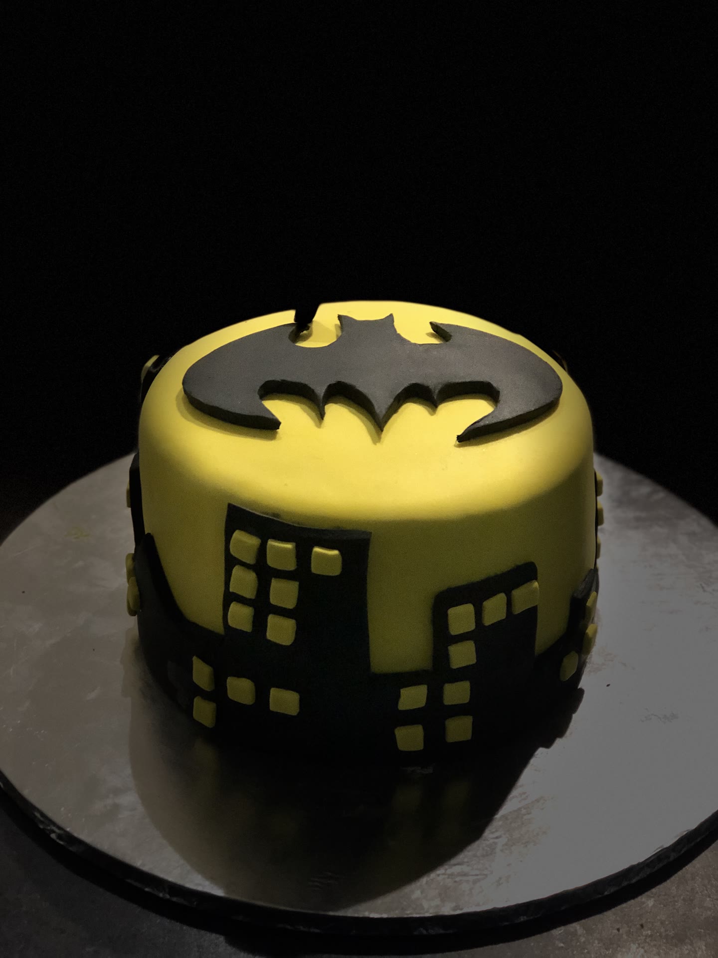 A yellow cake with a black city skyline cut around the base.