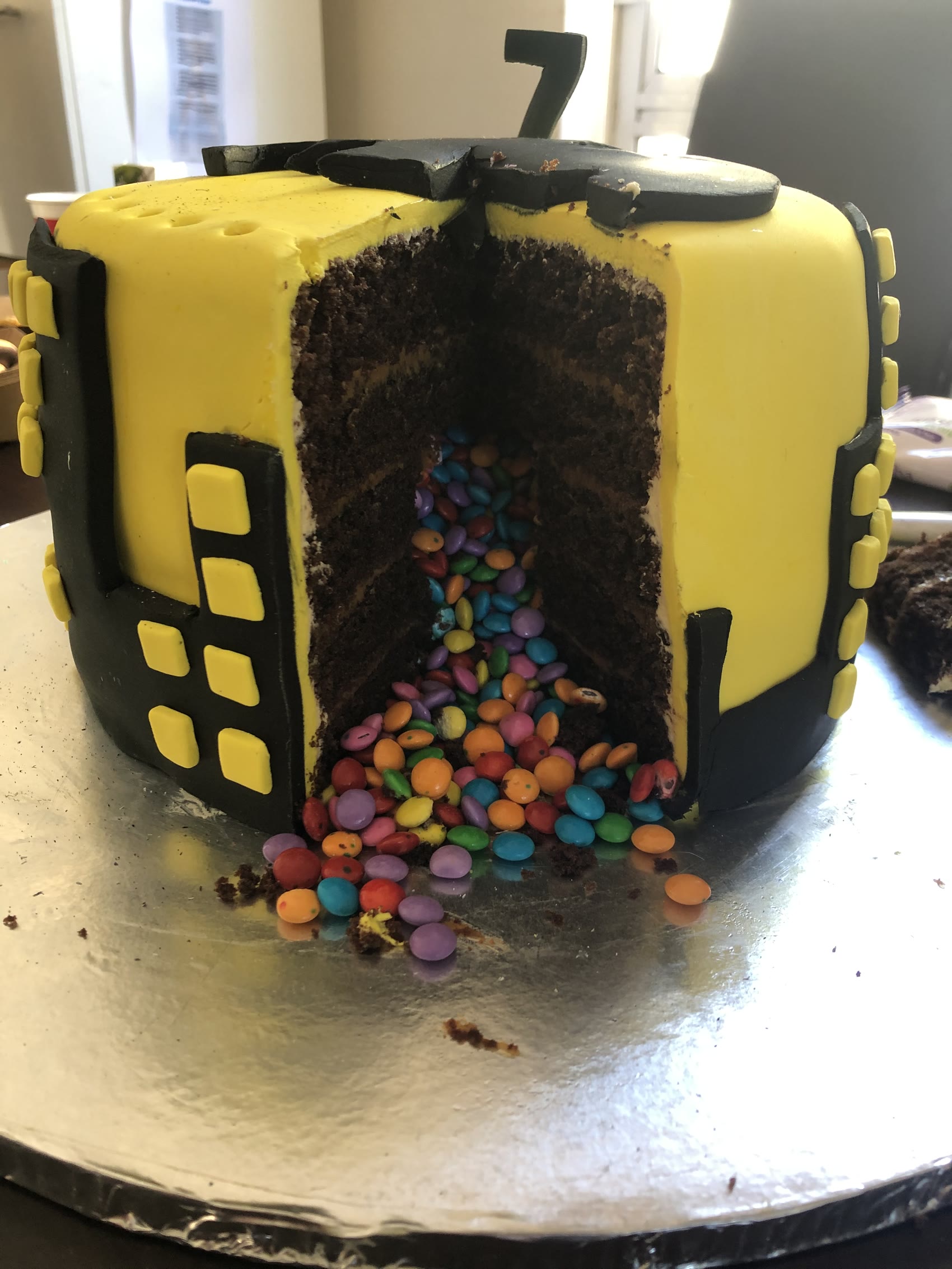 A yellow and black cake cut open with sweets spilling out of the middle.