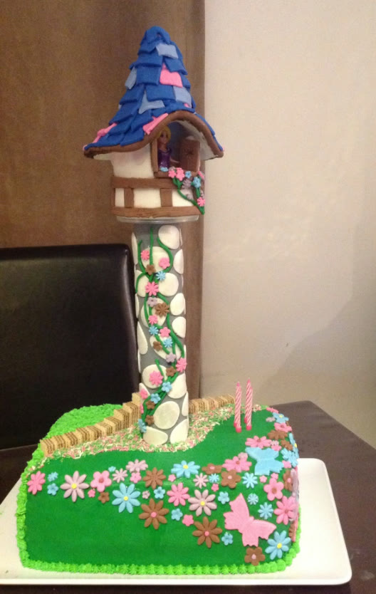 A tall tower cake with a tiled roof and stonework.