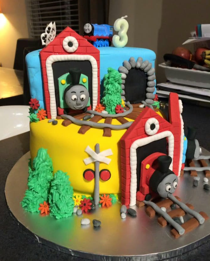 A tiered cake modelled as engine sheds with trains and track.